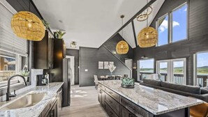 A modern kitchen with a large island, dark wood cabinetry, and pendant lighting. - Luxe at Lake Haven - Lakefront pool & hot tub (Sevierville)