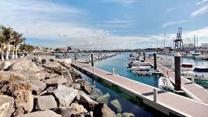 Una marina con barcos amarrados, un muelle y una costa rocosa.