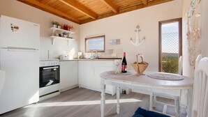 Una cocina con electrodomésticos blancos, una mesa de comedor y un ventanal con vistas.