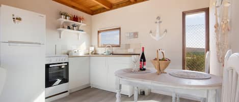 Una cocina con electrodomésticos blancos, una mesa de comedor y un ventanal con vistas.