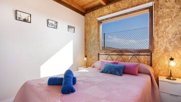 A bedroom with a bed, pillows, a window, and a nightstand.