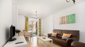 Ein Wohnzimmer mit Fernseher, einer Couch, einem Couchtisch und einem Gemälde an der Wand.