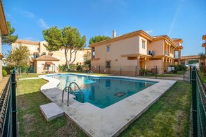 Un immeuble résidentiel doté d’une piscine, d’une cour clôturée et surplombant un ciel bleu dégagé.