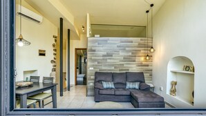 A modern living room with a sectional sofa, a dining table with chairs, a stone sculpture, and a wall with a wooden panel design. - Country House 'L Heura' with Private Terrace, Wi-Fi and Air Conditioning (Navata)
