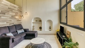 A modern living room with a grey sectional sofa, a round coffee table, and a large window with a view. - Country House 'L Heura' with Private Terrace, Wi-Fi and Air Conditioning (Navata)