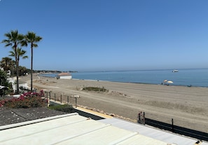 A beach view with palm trees, a sandy shore, and a boat in the water. - Vacation Home "Beach House El Saladillo" with Sea View, Private Tennis Court & Wi-Fi (Estepona, Saladillo Benamara)