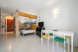 A compact room with a bunk bed, a desk with chairs, a television, and a staircase. - Holiday Apartment "Font De Mar" with Sea View, Private Terrace & Shared Pool (Salou)