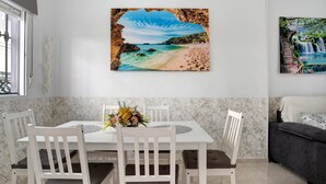 A dining area with a white table, four chairs, and a vase of flowers. - Holiday Home "Casa Centro Historico Barbate" with Private Terrace and Wi-Fi (Barbate)