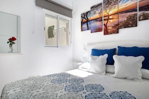 A bedroom with a bed, pillows, a window, and wall art.