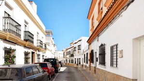 A narrow street lined with white buildings, parked cars, and stone-paved sidewalks. - Holiday Home "Casa Centro Historico Barbate" with Private Terrace and Wi-Fi (Barbate)