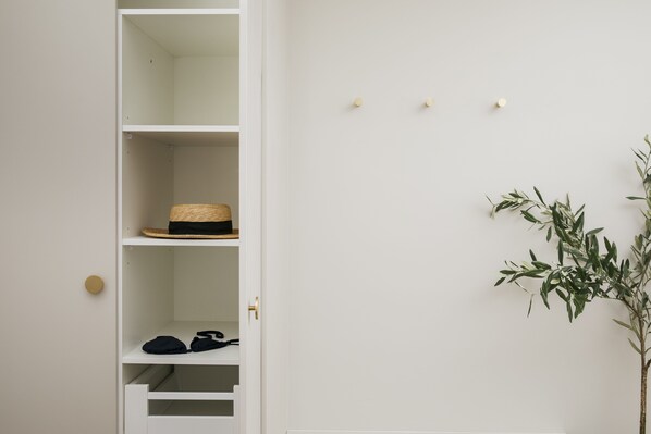 A white closet with shelves, a wicker basket, and a plant.