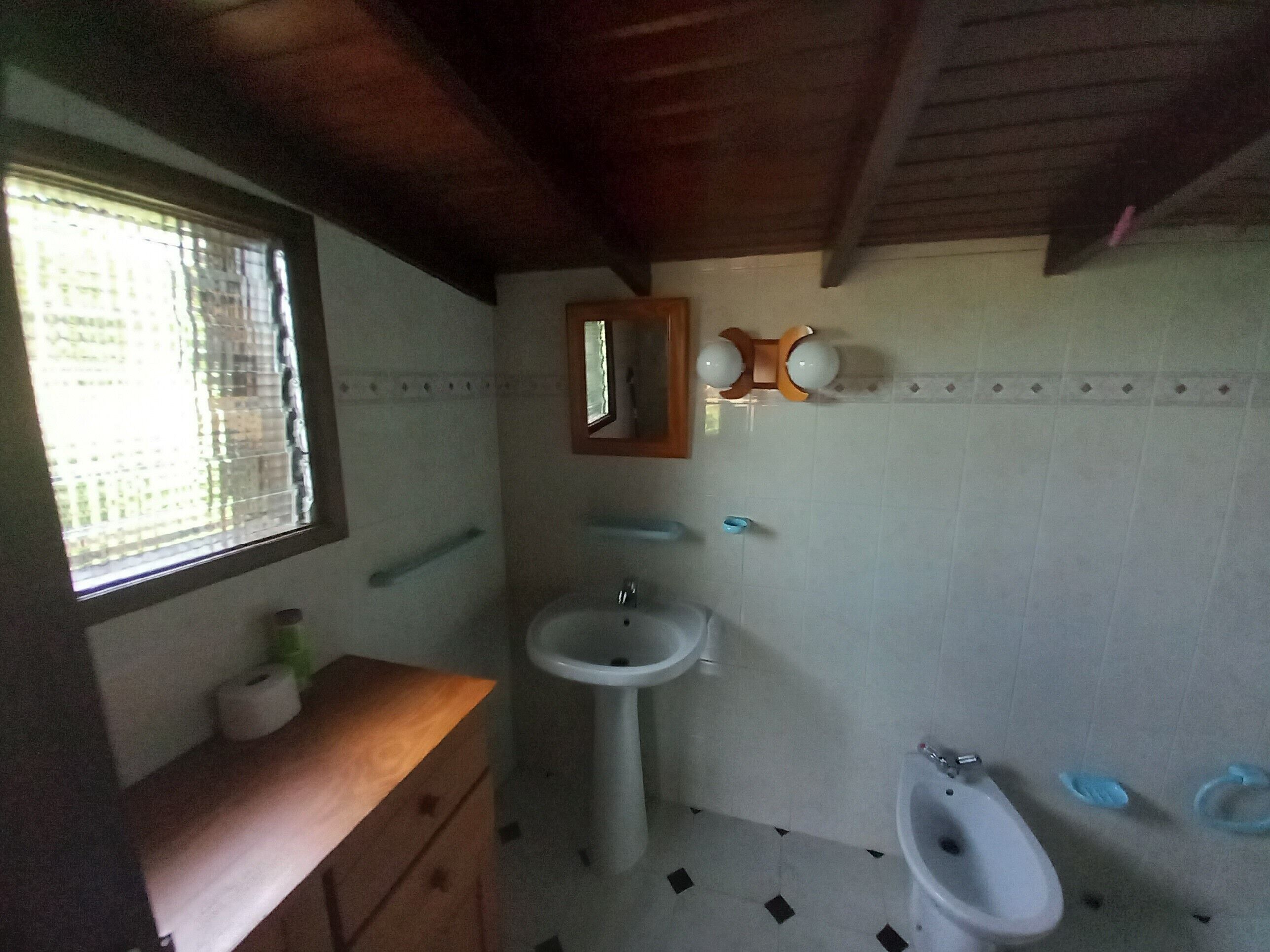 Un baño con tocador de madera, lavamanos, bidé y espejo.