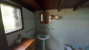 Un baño con tocador de madera, lavamanos, bidé y espejo.