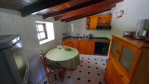 A kitchen with wooden cabinets, a sink, and a dining table with chairs. - Holiday Home 'La Carpintera' with Sea View, Private Terrace and Wi-Fi (Tijarafe)