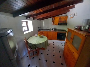 A kitchen with wooden cabinets, a sink, and a dining table with chairs.