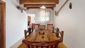 A wooden dining table with chairs, a hanging light fixture, and a curtain with polka dots.