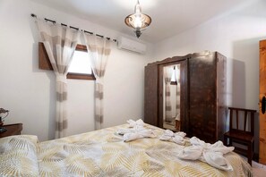 Een hotelkamer met een bed, een kast, een spiegel en een raam met gordijnen.