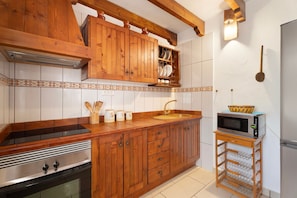A kitchen with wooden cabinets, a built-in microwave, and a sink.