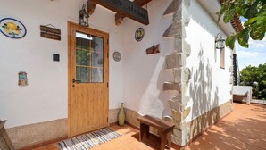 A rustic building with a wooden door, a welcome sign, and a bench outside.