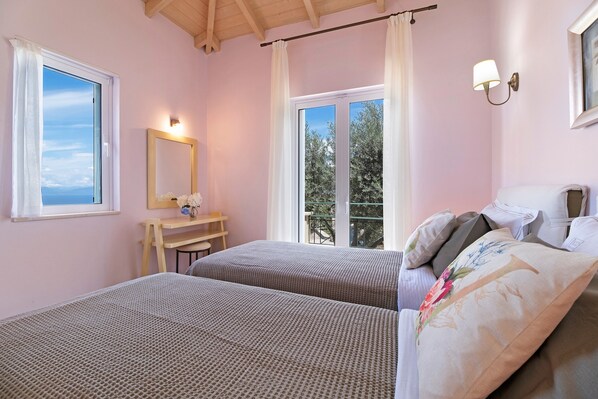 A bedroom with two beds, a desk, a mirror, and a window with curtains.