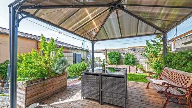 A covered patio with a table and bench, surrounded by greenery and a wooden deck. - Guest House 'Domaine De Pharaon' with Shared Terrace, Wi-Fi and Air Conditioning (Morlaix)