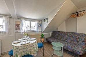 A dining area with a table set for two, a sofa, and a radiator. - Guest House 'Domaine De Pharaon' with Shared Terrace, Wi-Fi and Air Conditioning (Morlaix)