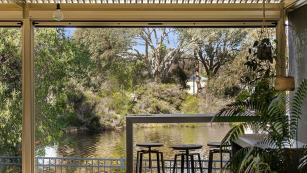 Un espace extérieur abrité, aménagé avec des sièges, et offrant une vue sur une rivière et la végétation environnante.