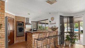 Une cuisine moderne avec un mur en briques, un four encastré et des tabourets de bar.
