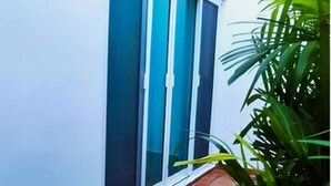 A building with a white exterior, a tiled roof, and a window with a blue frame. - Departamentos Villas Capdeviel (Cancun)