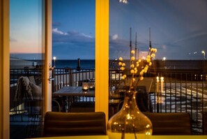 Enjoy a meal with a view of the ocean from our restaurant's dining area, featuring tables and chairs.