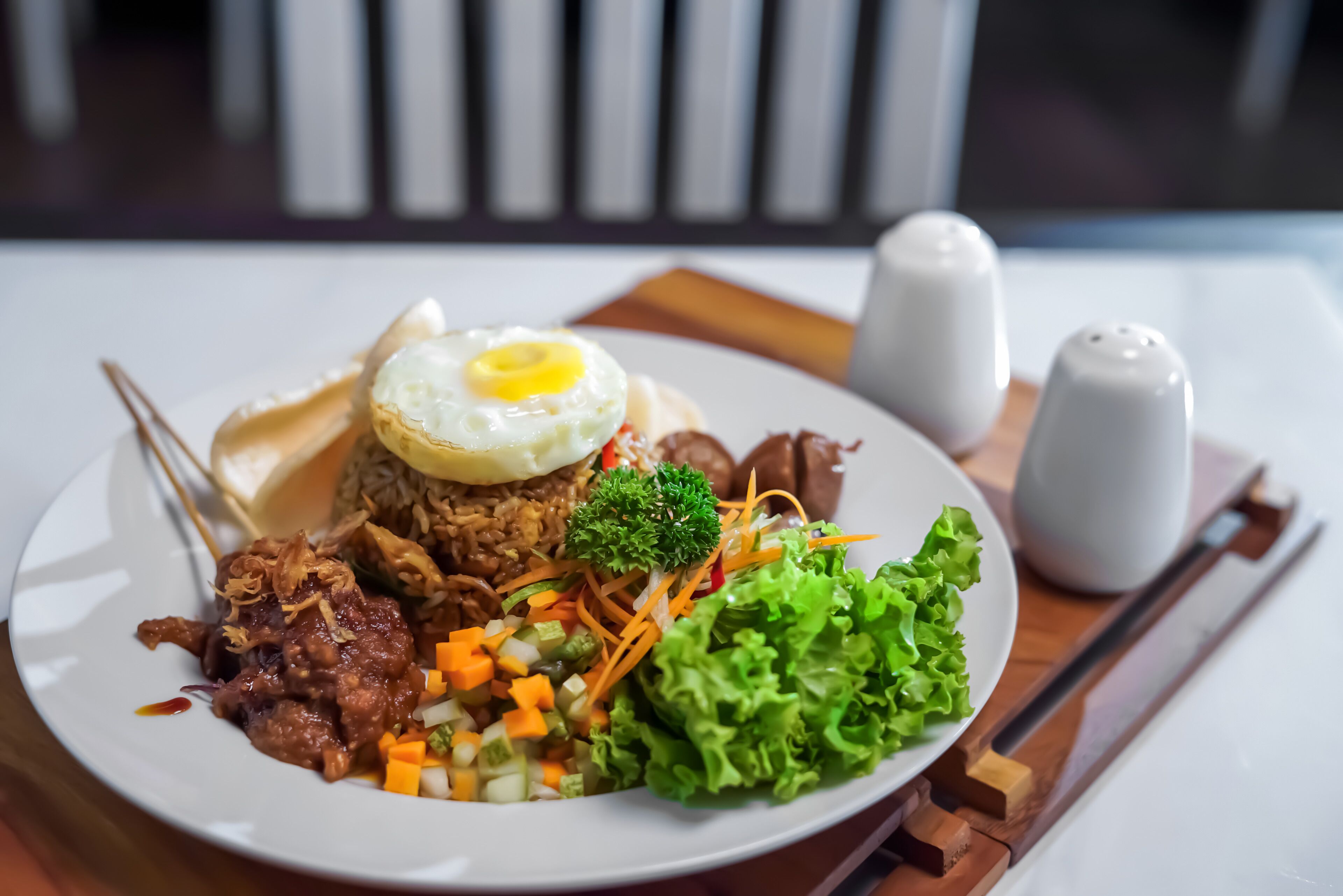 Une assiette contenant un plat composé d’un œuf frit, de riz, de viande et de légumes.