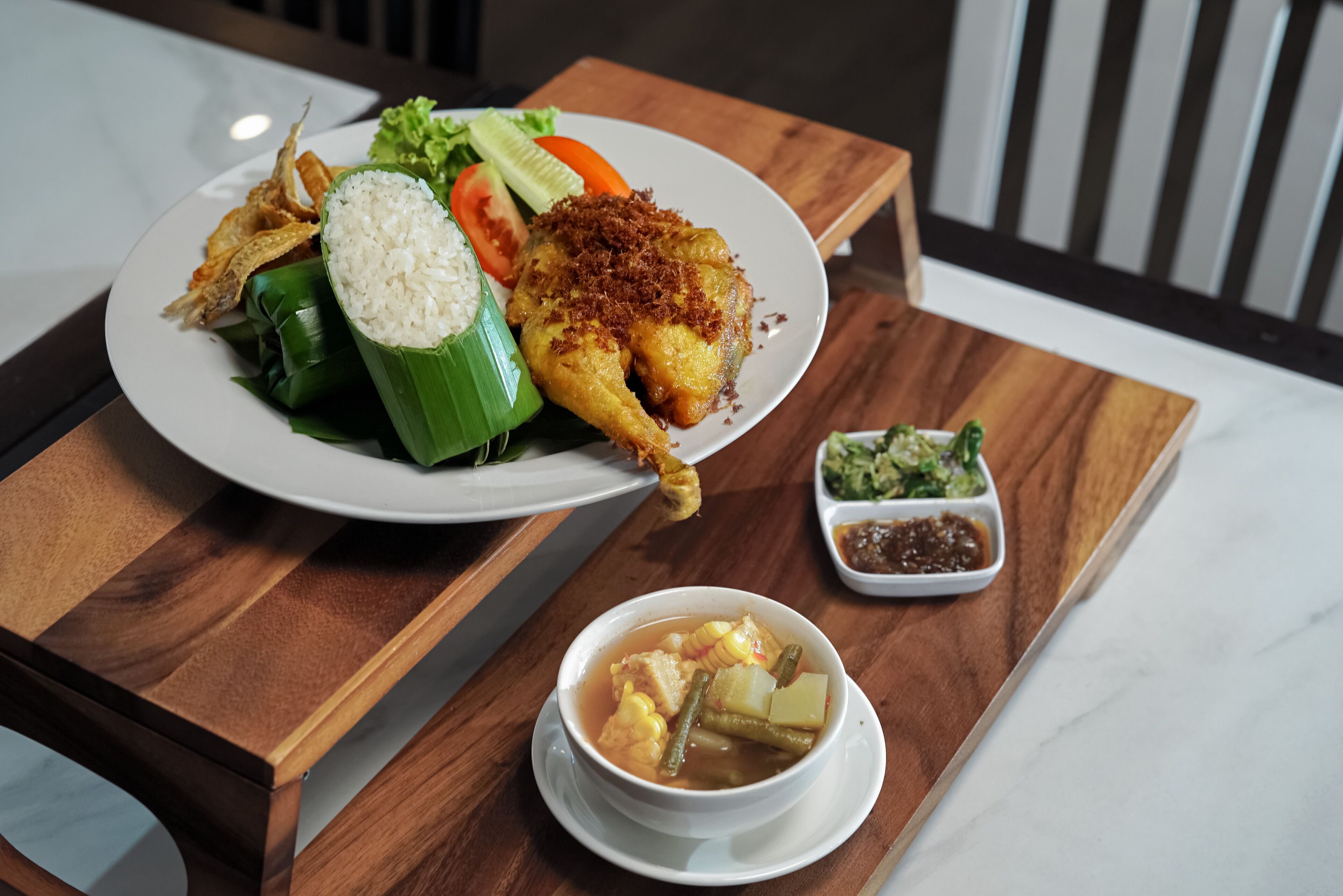 A meal with rice, vegetables, and a chicken dish on a wooden table.