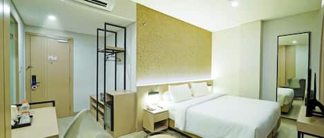 Habitación de hotel con cama, mesita de noche, silla, armario y espejo.