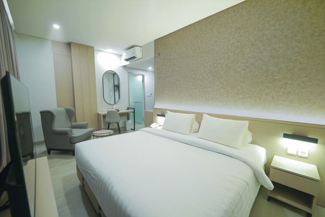 Une chambre d’hôtel avec un grand lit, un bureau avec une chaise, une télévision et un miroir.