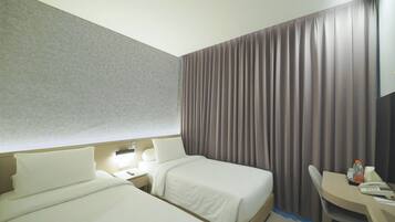 A hotel room with two beds, a desk, and a chair.