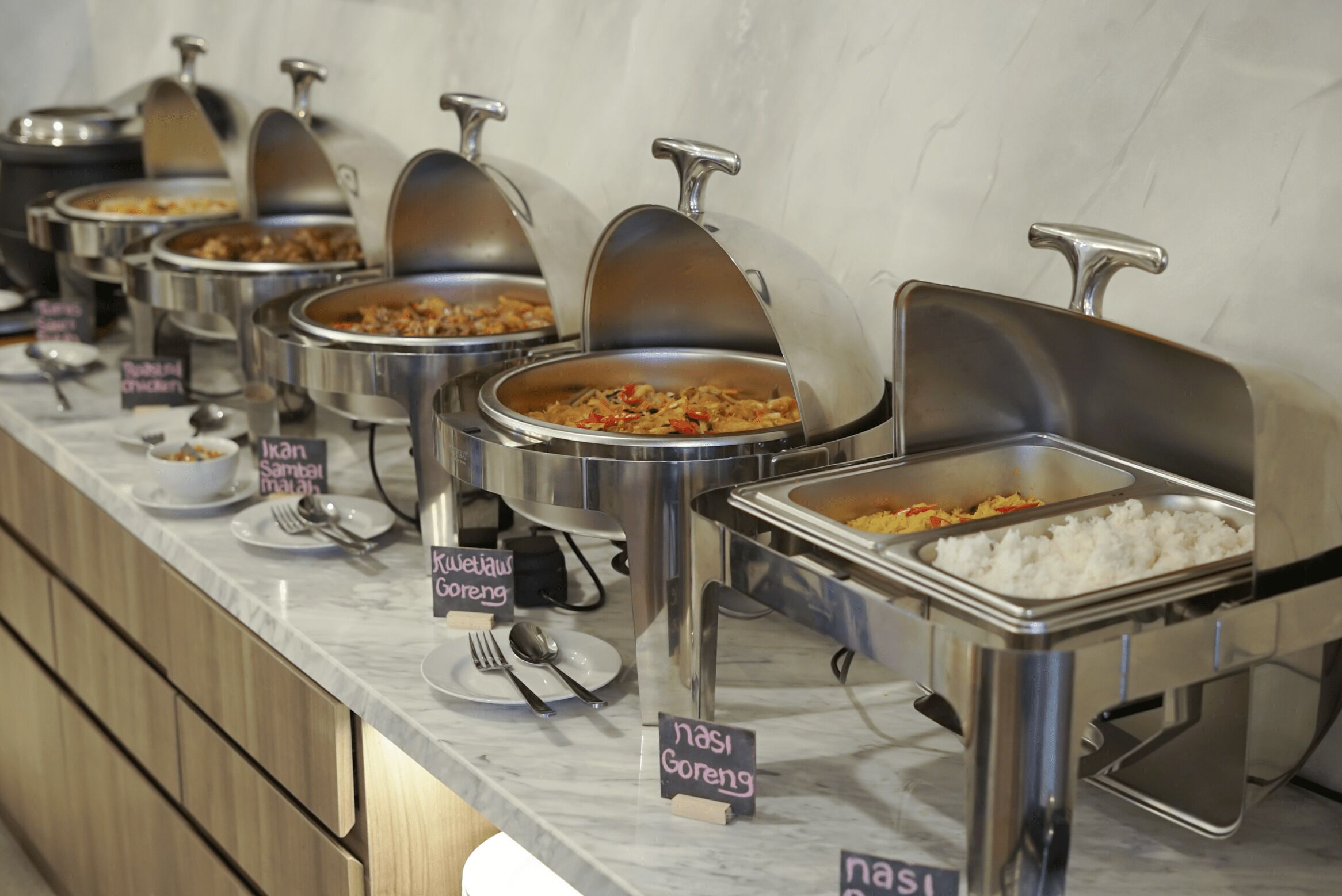 A buffet with labeled food stations including nasi goreng, soup, and rice.