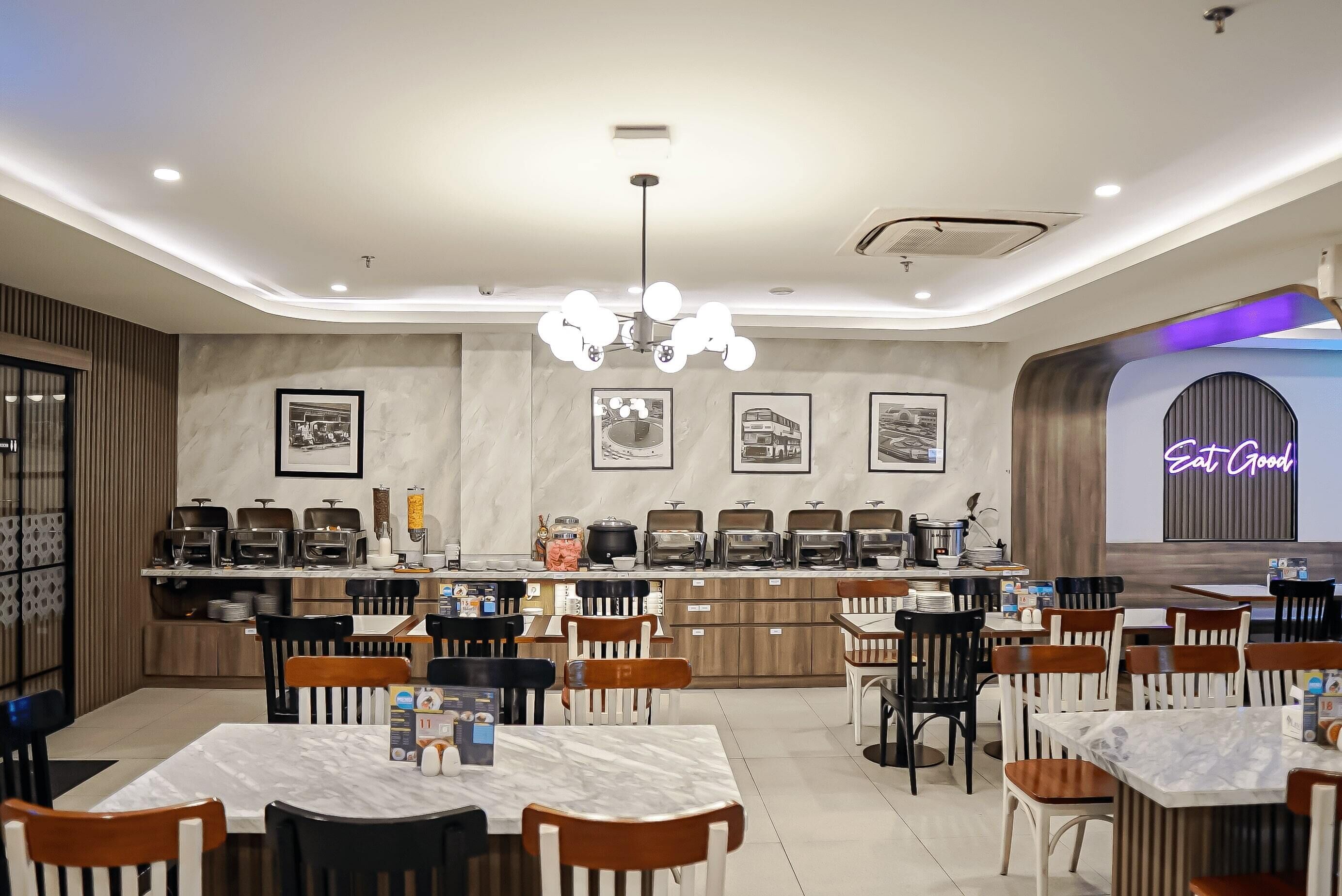 A modern restaurant with marble tables and chairs, a central counter with food display, and framed pictures on the walls.