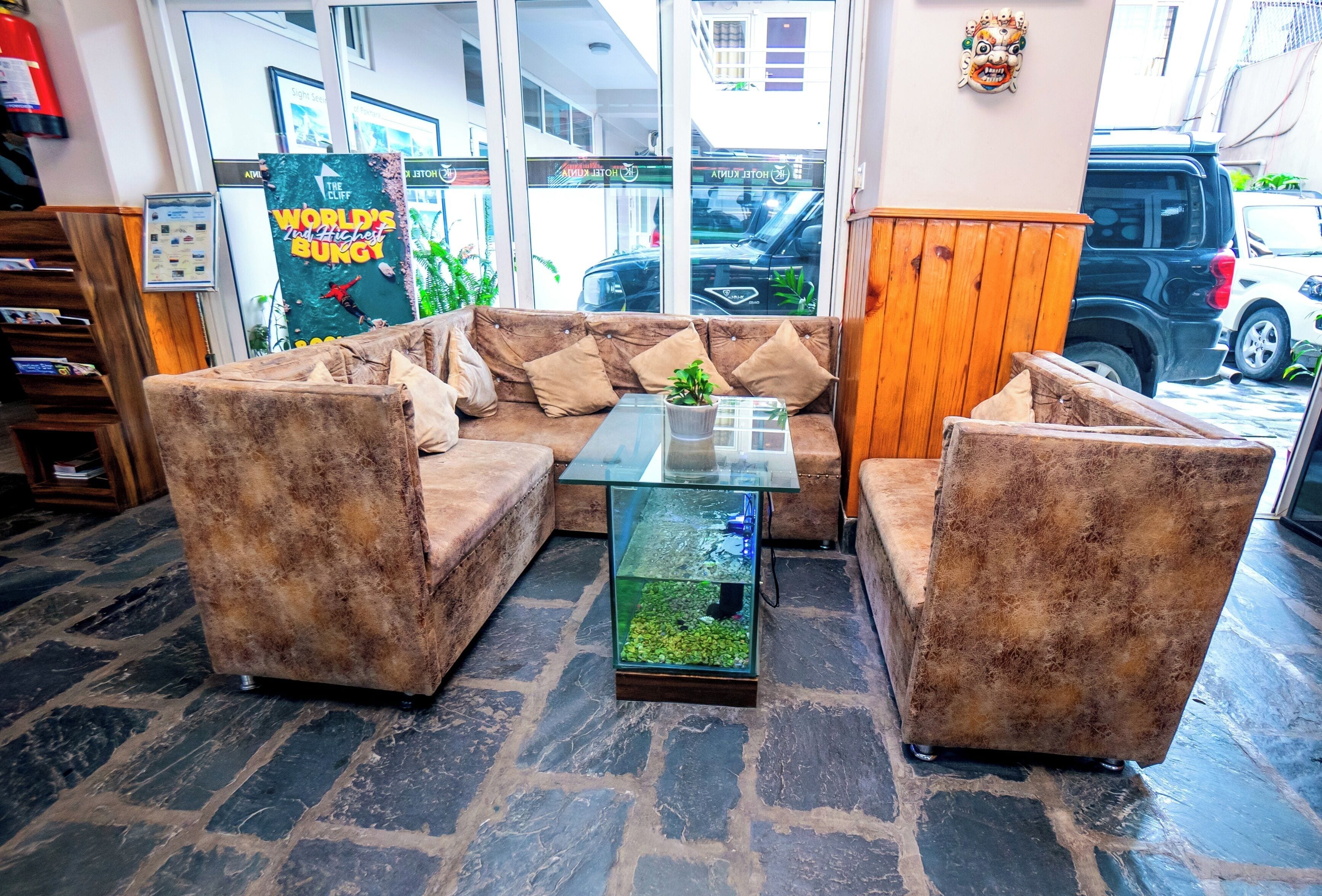 En hyggelig lobby med en sofa, to lænestole, et sofabord i glas og et akvarium.