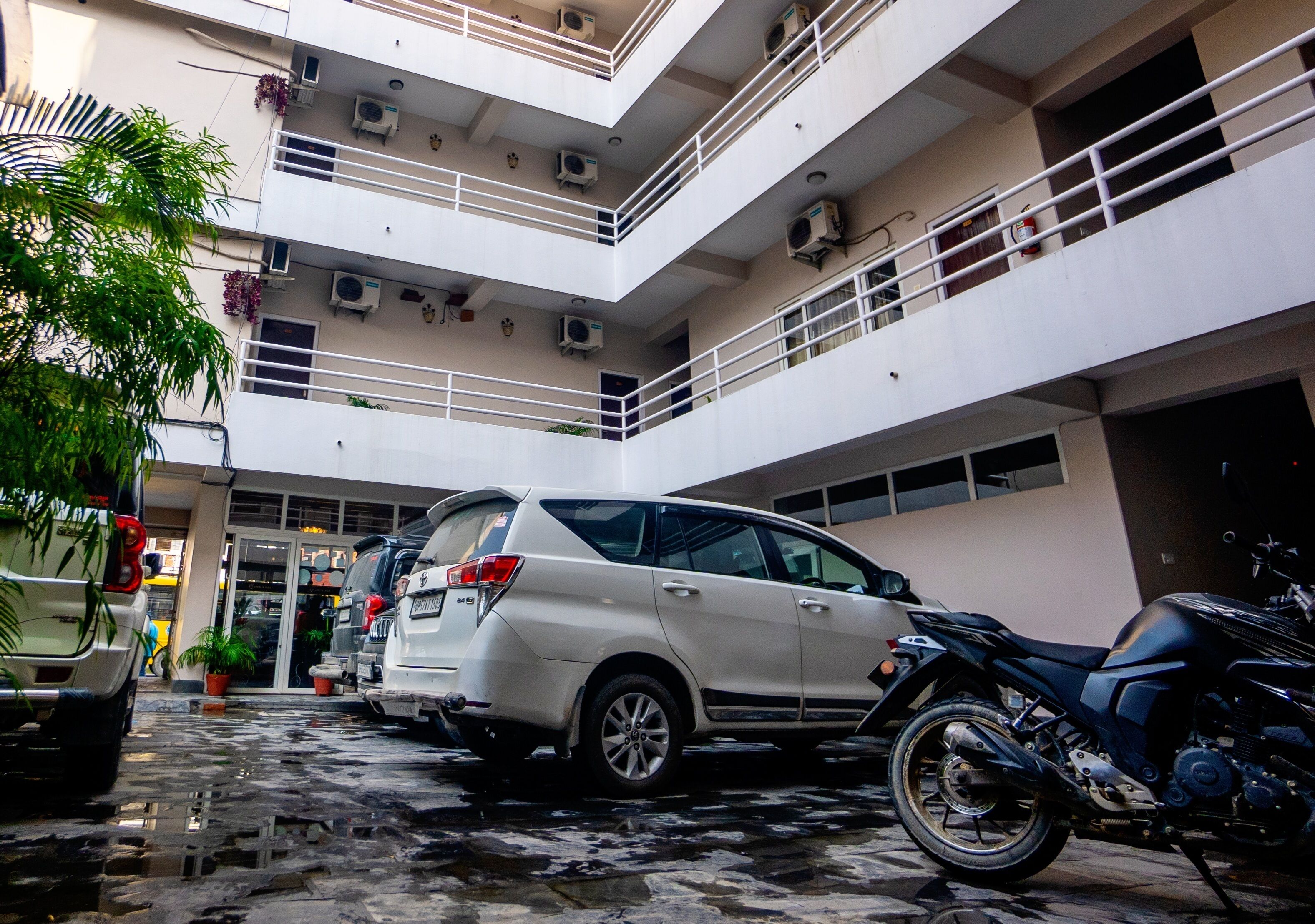 Un parking à plusieurs niveaux où sont garés une voiture blanche et une moto.
