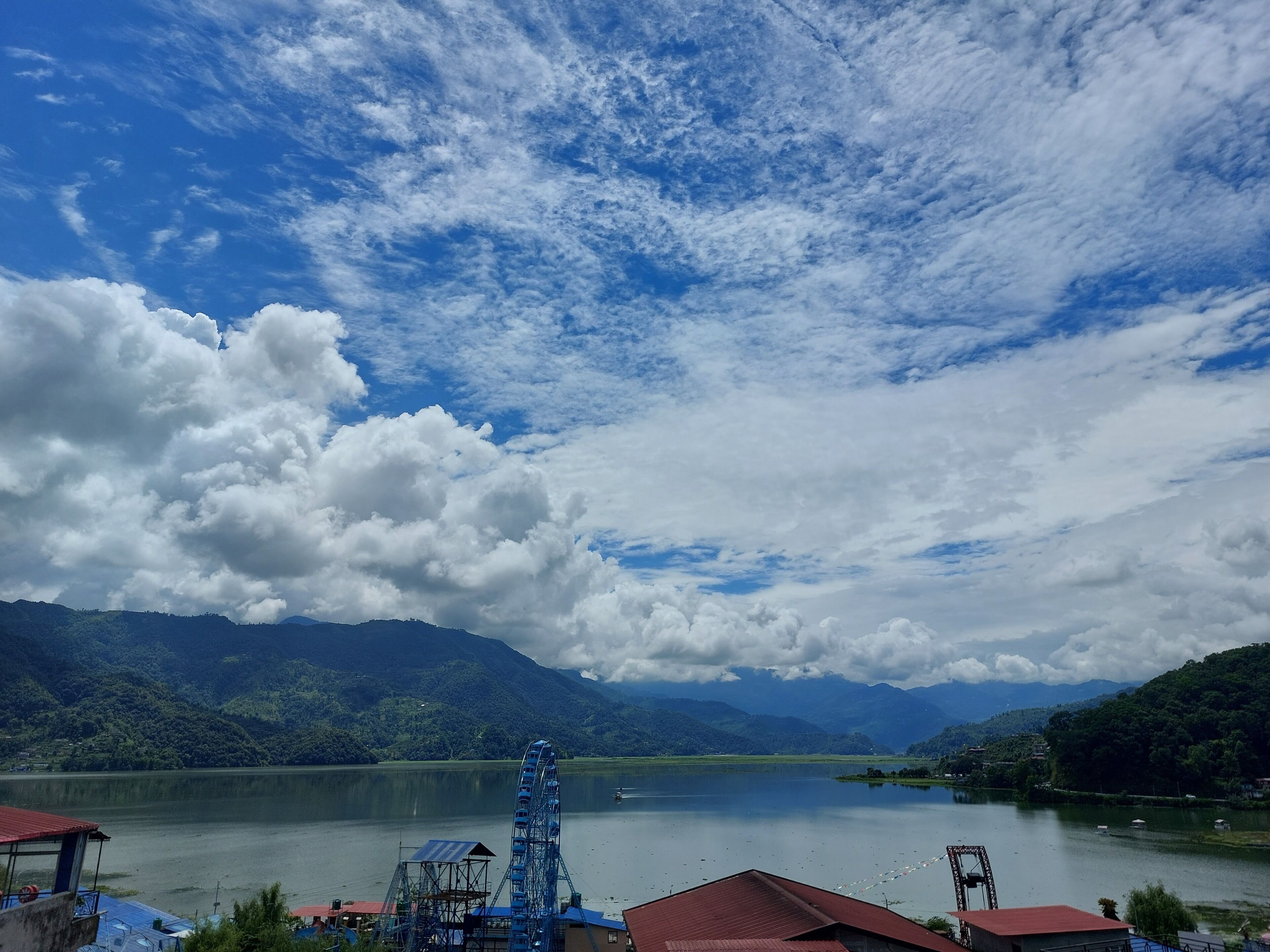A lake with a Ferris wheel and mountains in the background.