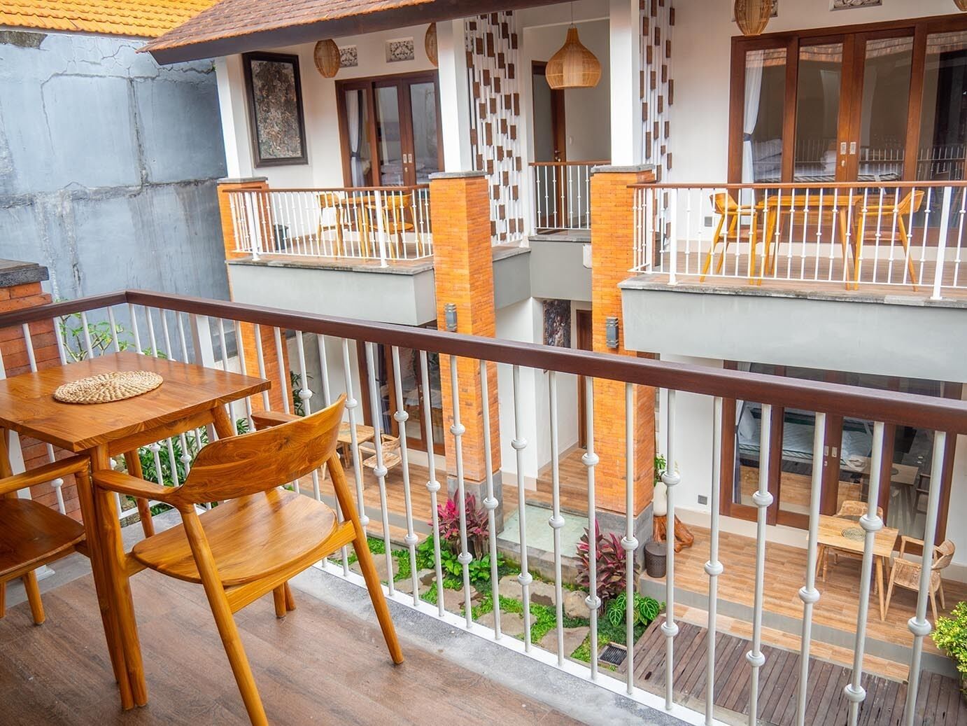 A multi-level outdoor balcony with wooden furniture and a small garden area.
