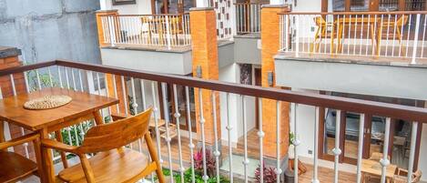 A multi-level outdoor balcony with wooden furniture and a small garden area.