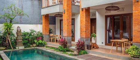 A modern hotel with a pool, outdoor seating, and a garden area.