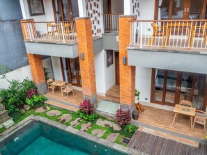 A multi-level residential building with a swimming pool, outdoor seating, and a garden area. - Arumasta Ubud (Ubud)