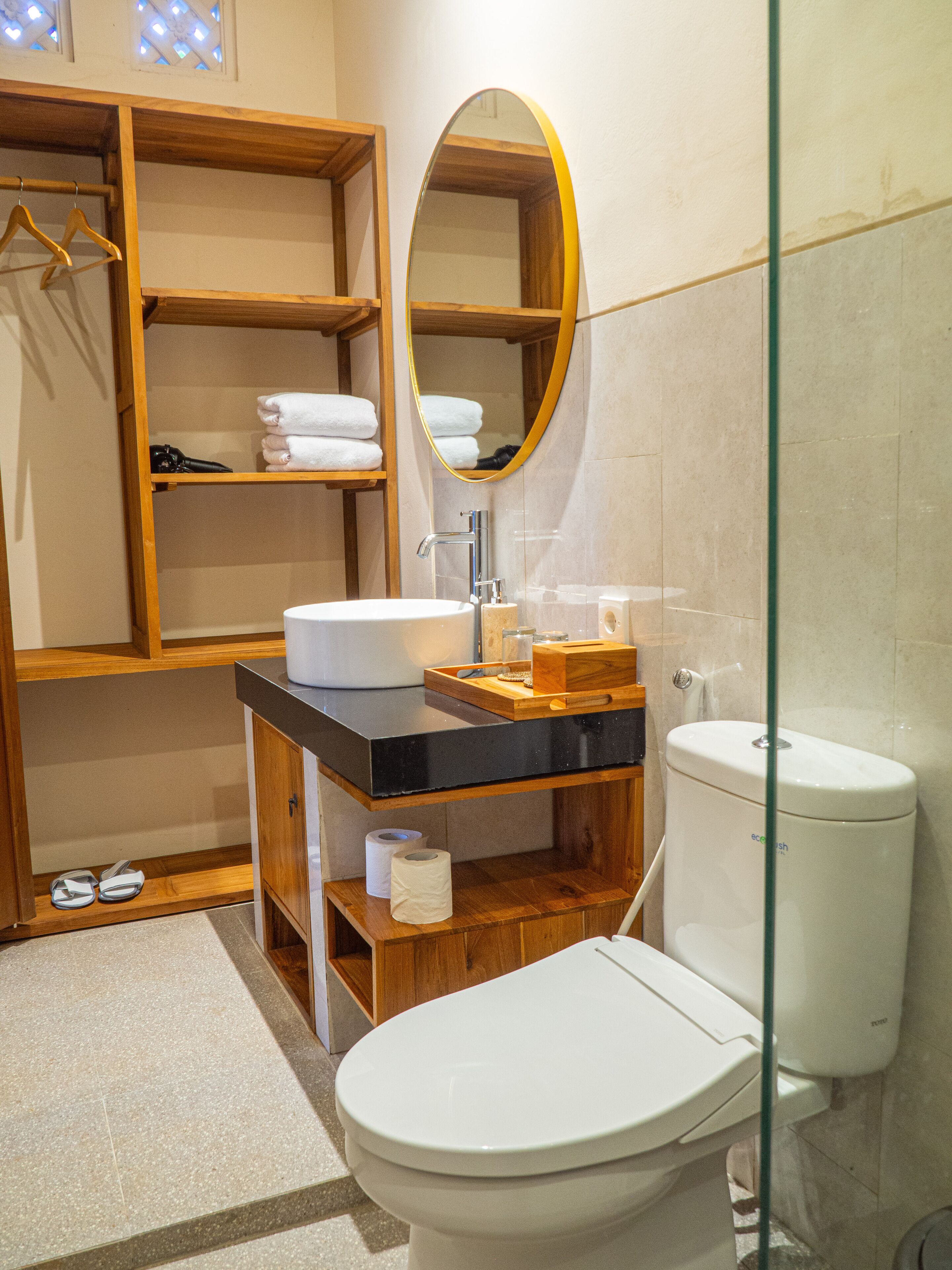 A bathroom with a wooden vanity, a white toilet, and a mirror.