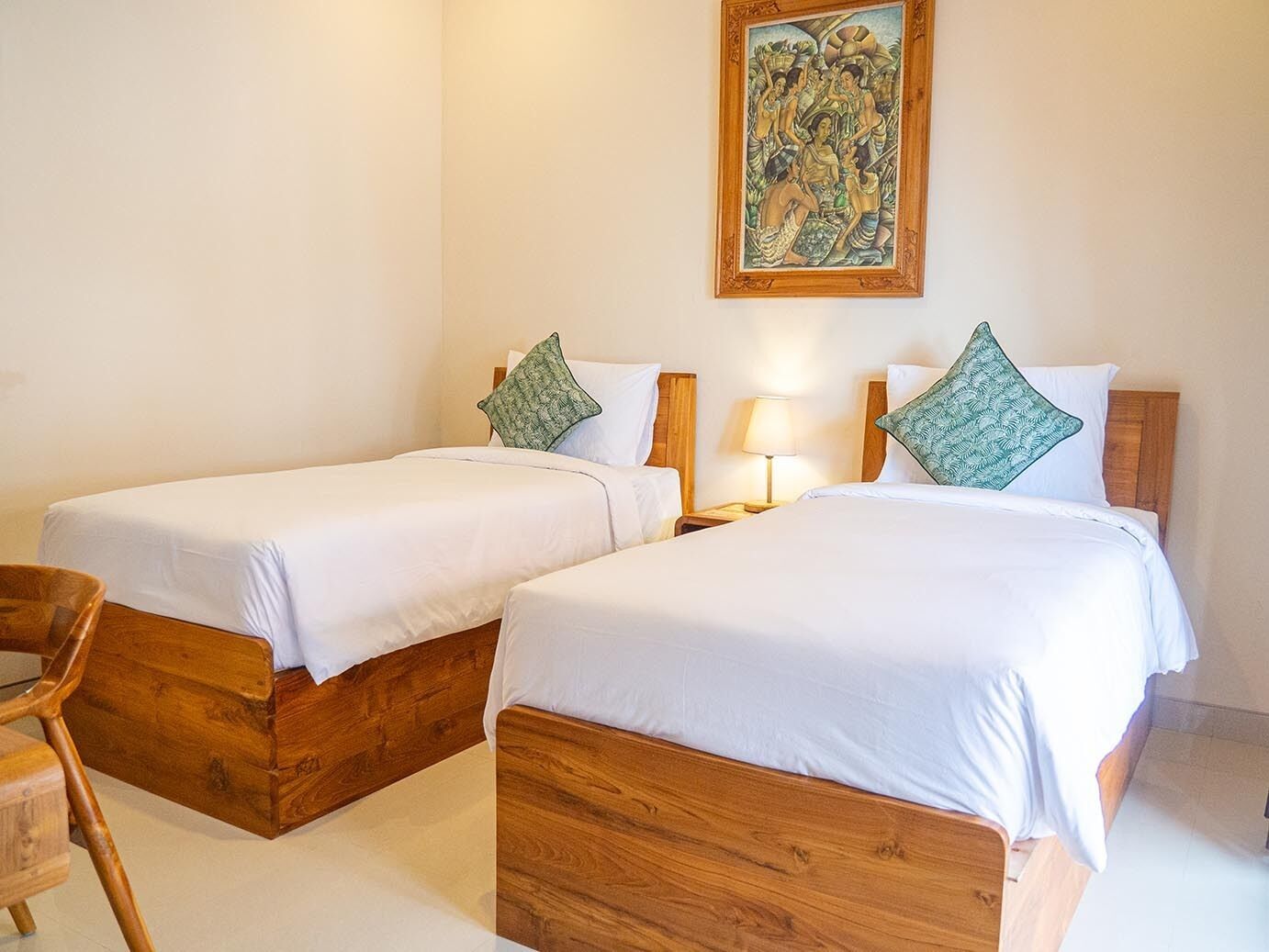 A hotel room with two wooden beds, white bedding, and a painting on the wall.