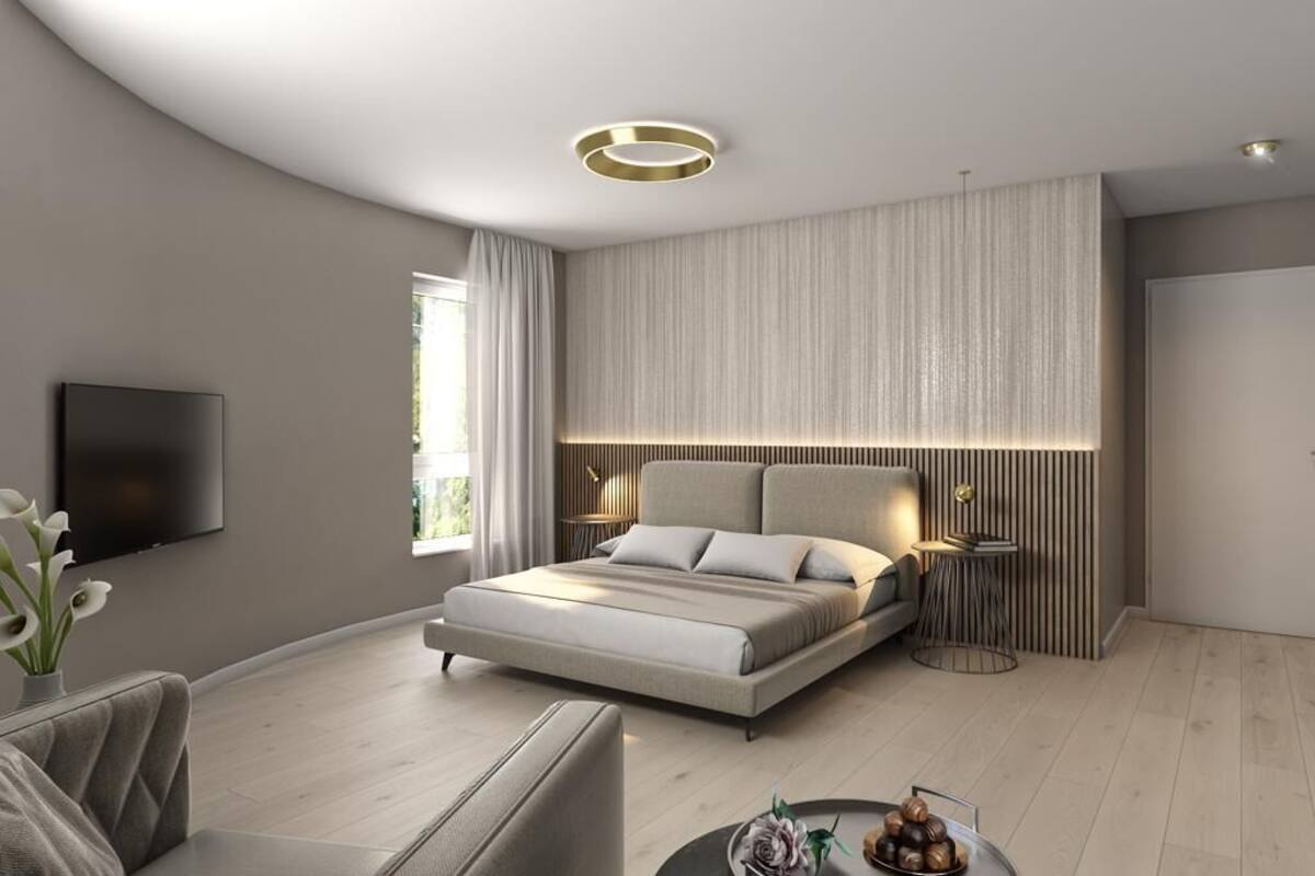 Une chambre moderne avec un grand lit, une télévision et un luminaire rond au plafond.