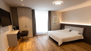 Ein modernes Hotelzimmer mit einem großen Bett, einem Schreibtisch und einem Kleiderschrank.