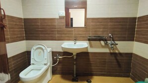 A bathroom with a toilet, sink, and shower. - Annai Residency (Mayiladuthurai)