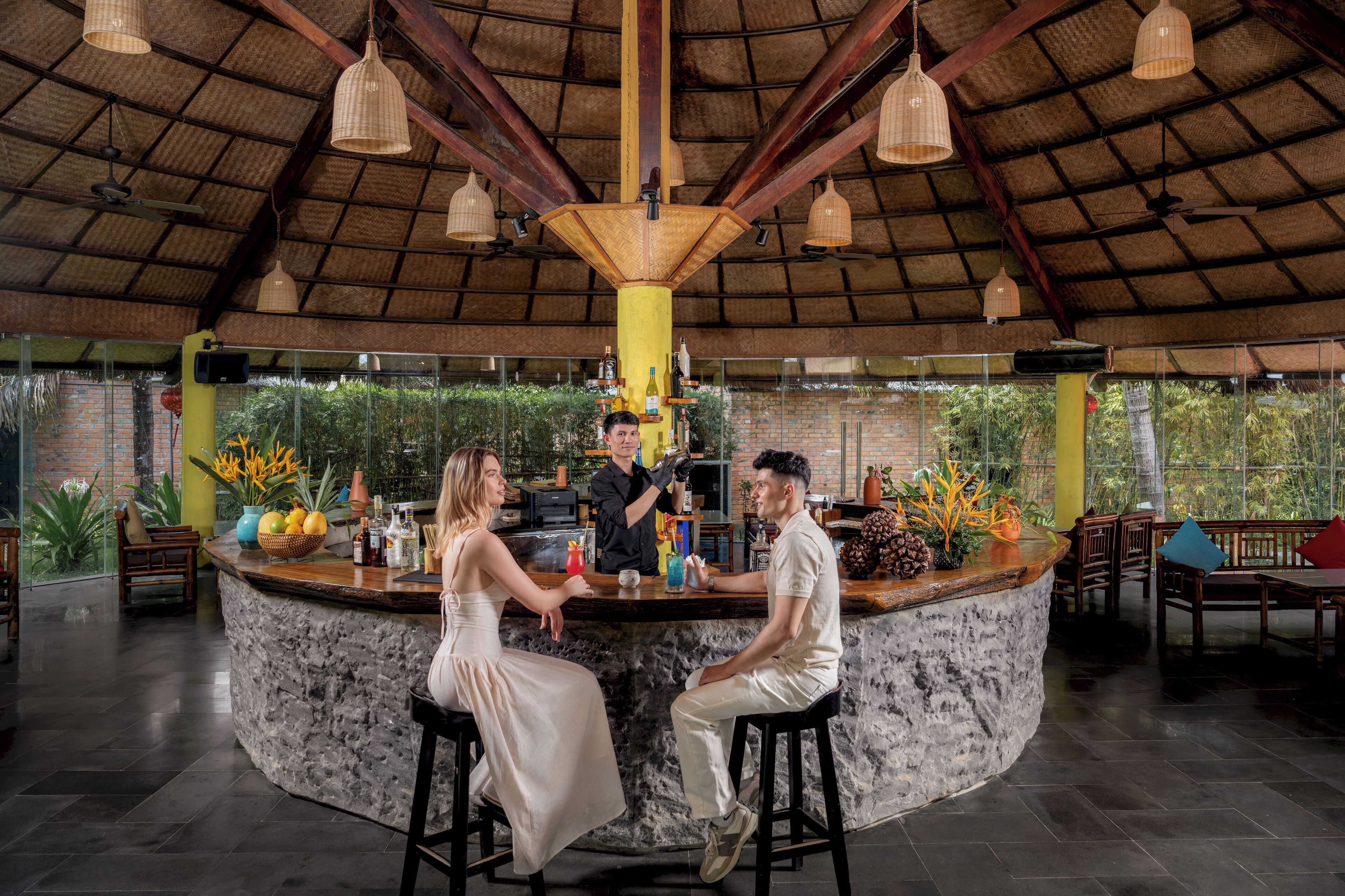 A bar area with a stone counter, wooden chairs, and hanging lights.